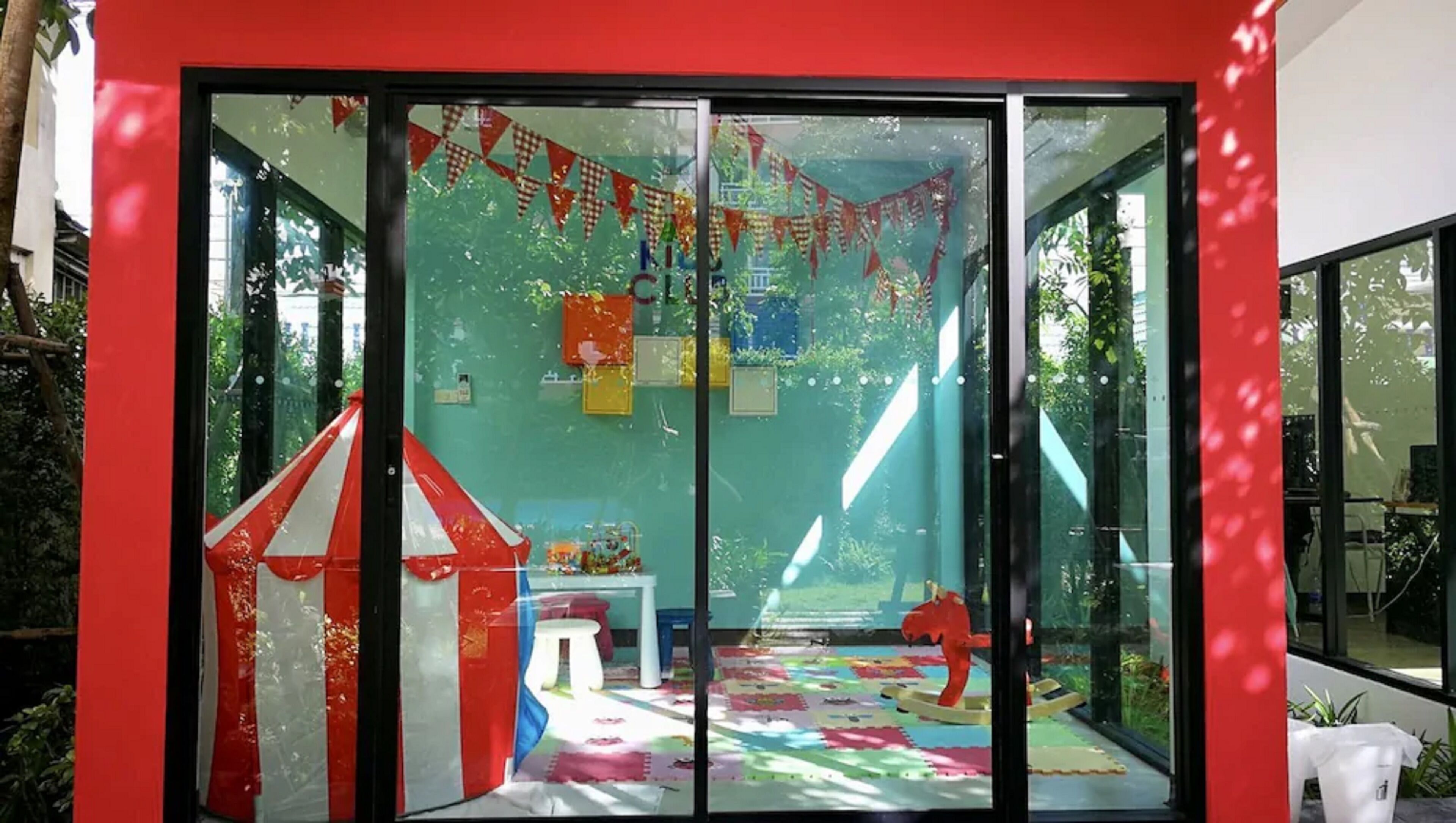 A brightly colored room with a red and white striped tent, a small table, and a rocking horse.