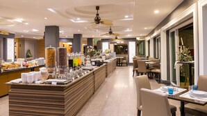 A hotel lobby with a buffet area, seating arrangements, and a reception desk.
