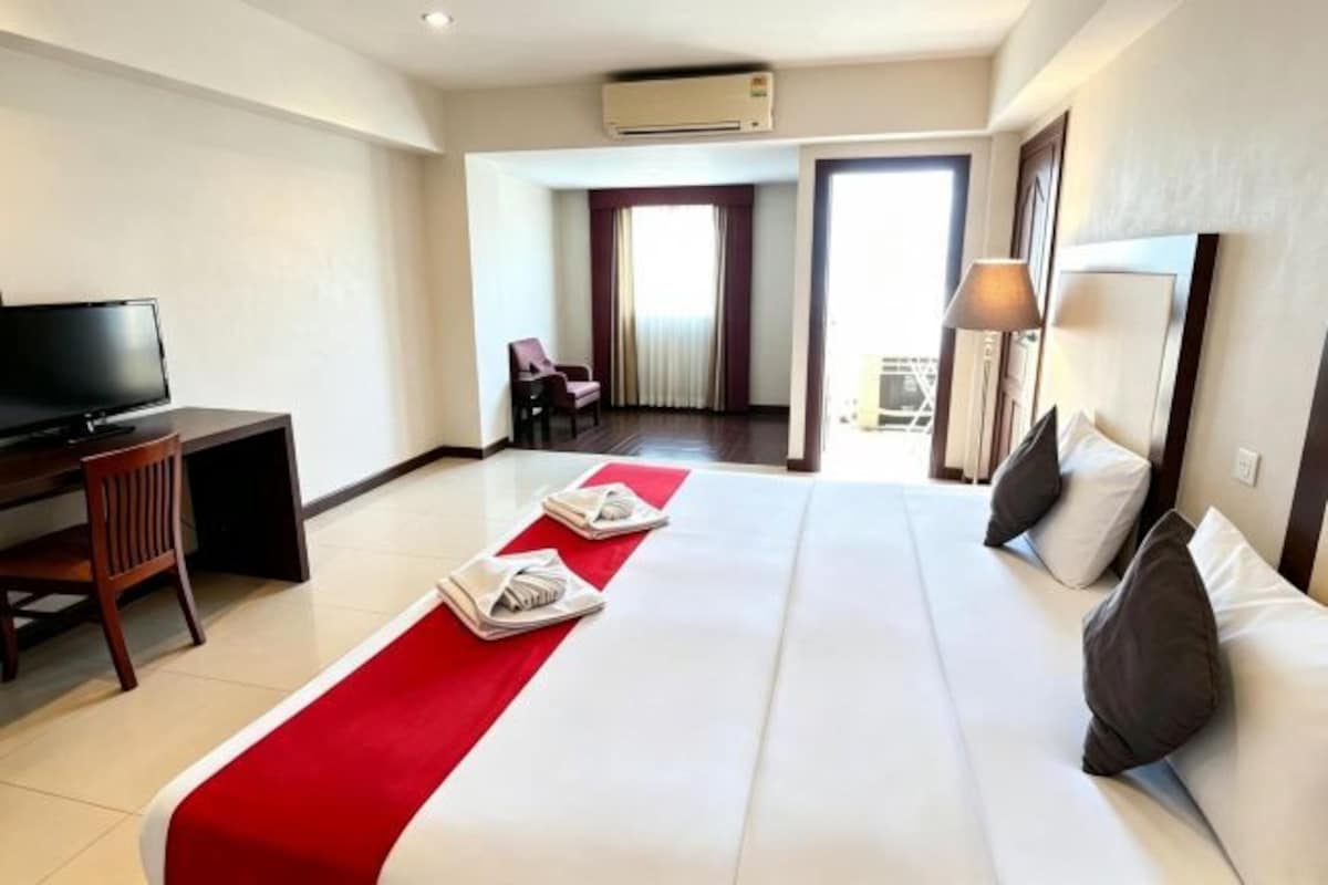 Une chambre d’hôtel avec un lit, un bureau, une télévision et une chaise.