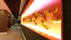 A hallway with a red wall and golden wall art.