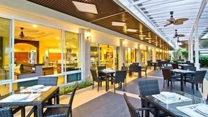 An outdoor dining area with tables and chairs, a covered walkway, and a view of the restaurant inside.