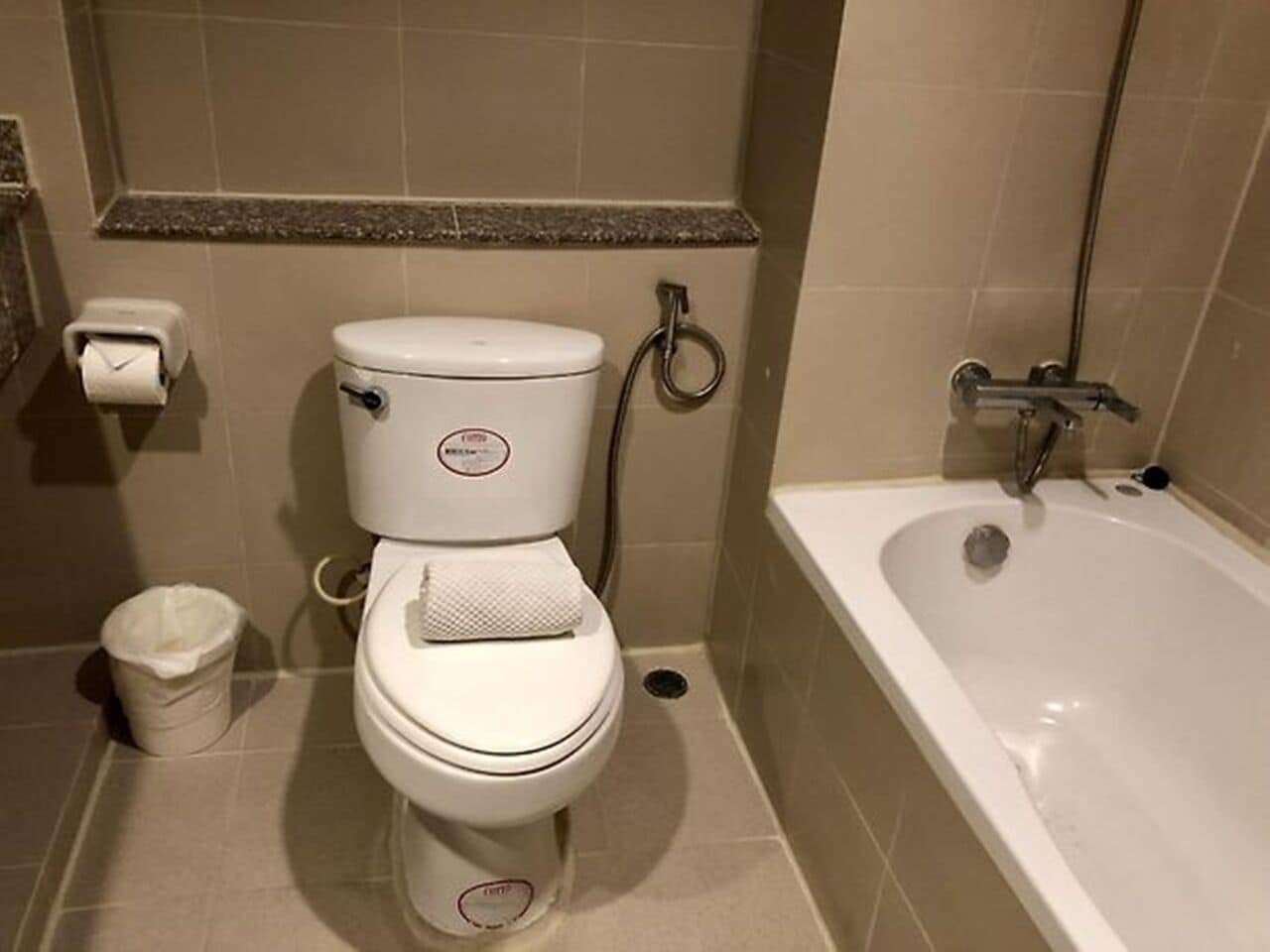 A bathroom with a toilet, a trash bin, and a bathtub.