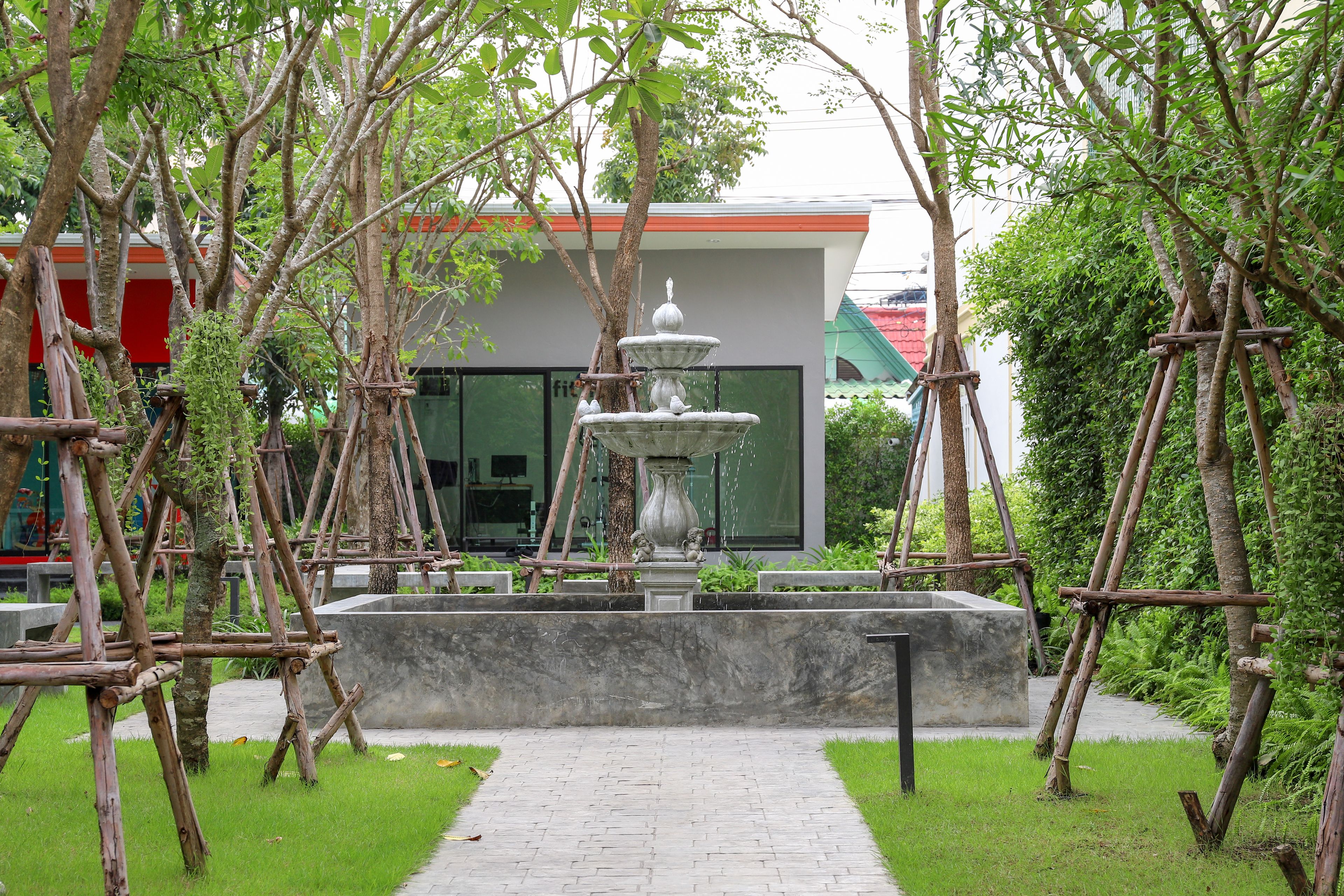 A garden with a central fountain, surrounded by trees and a pathway.