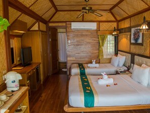 A hotel room with two beds, a TV, a coffee maker, and a wooden ceiling.