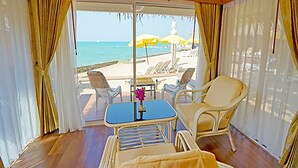 Une chambre avec vue sur la plage, une table avec des chaises et une petite table sur laquelle est posé un vase.