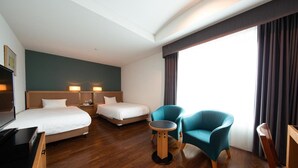 Una habitación de hotel con dos camas, televisión, una mesita y una silla.