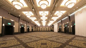 Un amplio salón con alfombra, candelabros, puertas y suelo con diseño.