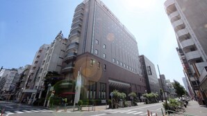 Un hotel de varios pisos con un diseño moderno, que destaca por una entrada imponente y un amplio frente de vidrio.
