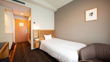 A hotel room with a single bed, a desk, a chair, a nightstand, and a framed picture on the wall.