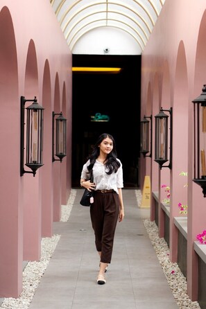 A corridor with pink walls, black lanterns, and a person walking.