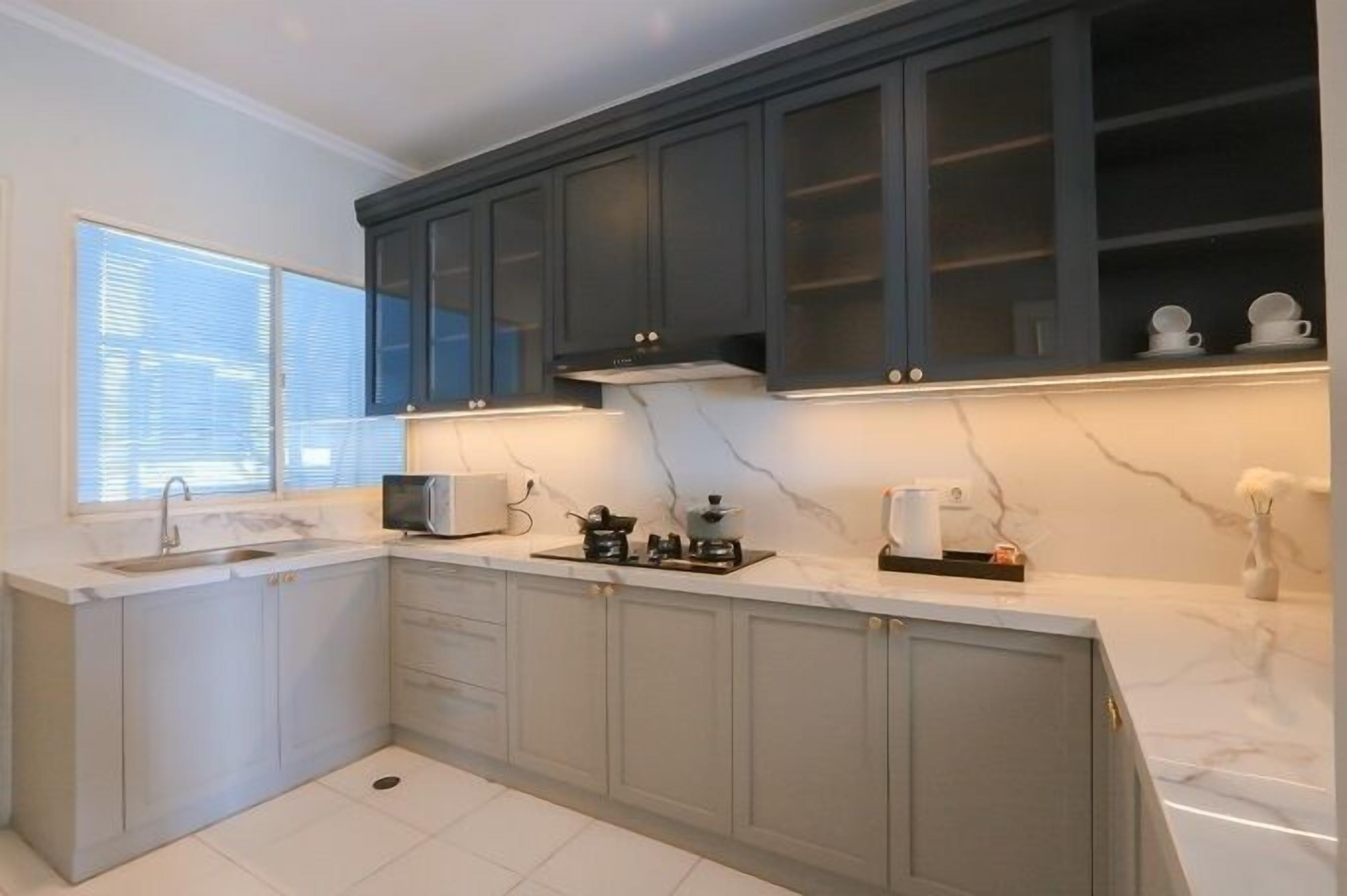 A modern kitchen with dark cabinets, a microwave, and a sink.