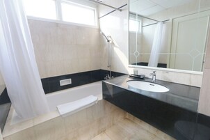 Uma casa de banho moderna com banheira, lavatório e um espelho grande.