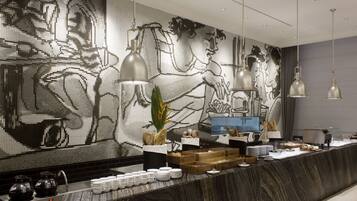 Um hall de hotel moderno com um grande painel de mosaicos, um balcão de recepção de mármore e iluminação pendente.