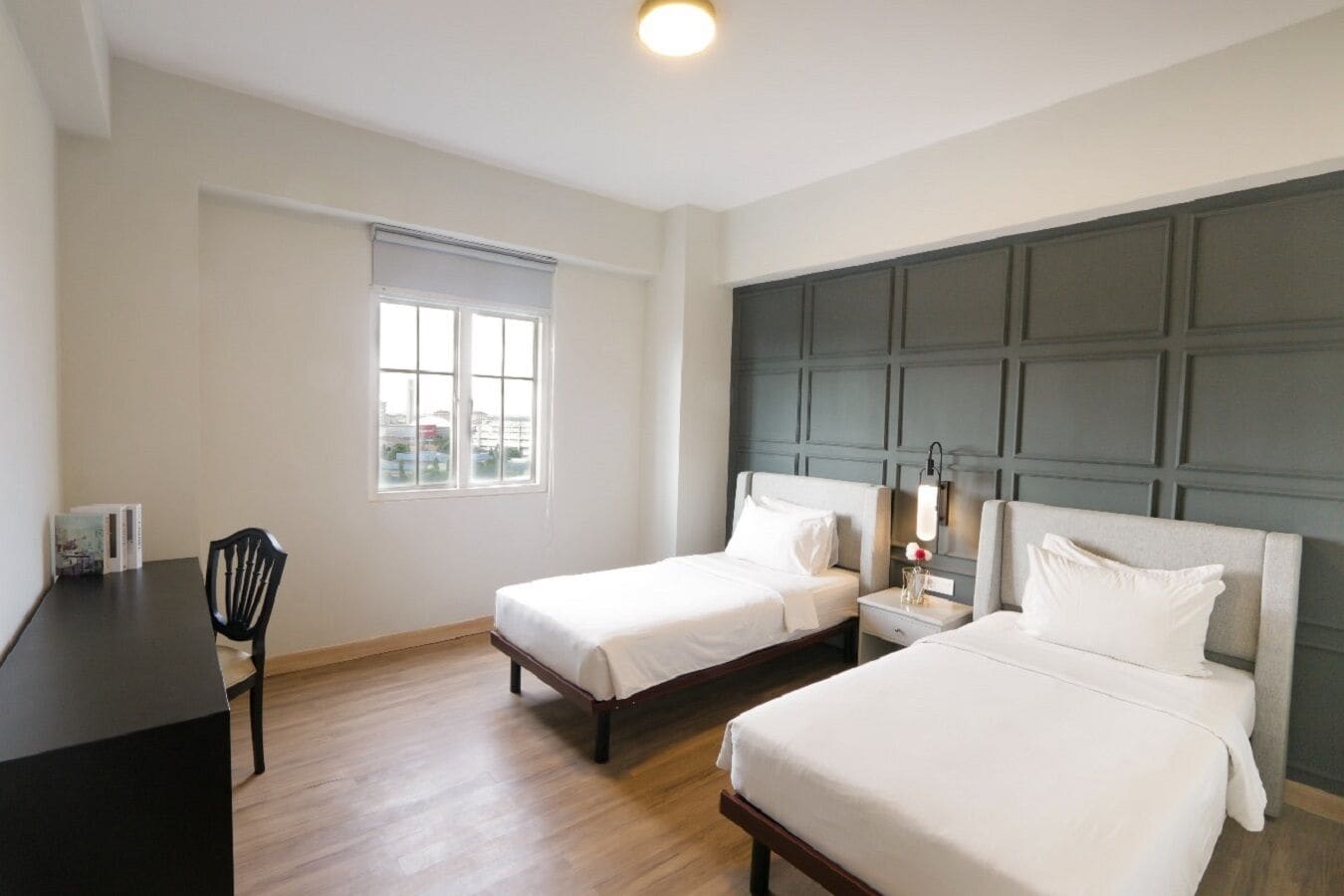 Una habitación de hotel con dos camas, un escritorio y una ventana.