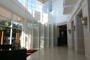 A spacious lobby with high ceilings, large windows, and a chandelier.