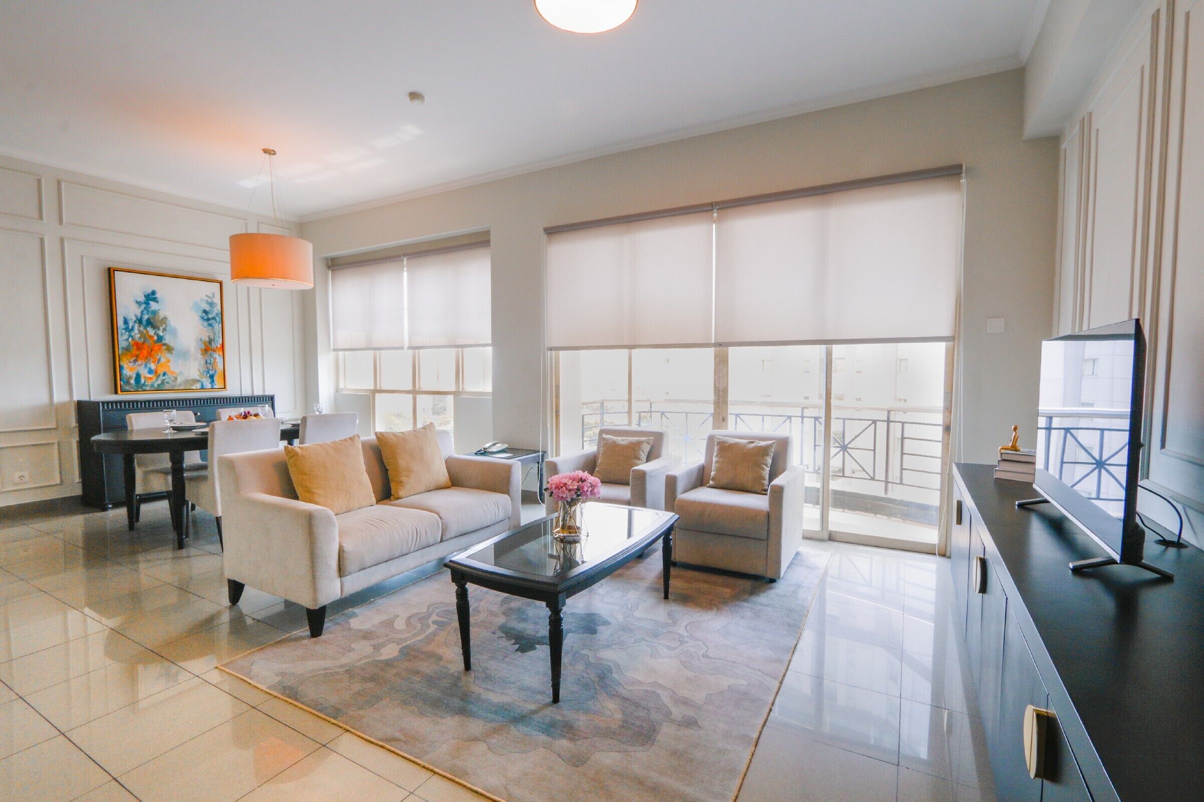 A spacious living room with a sofa, armchairs, a coffee table, and a television.