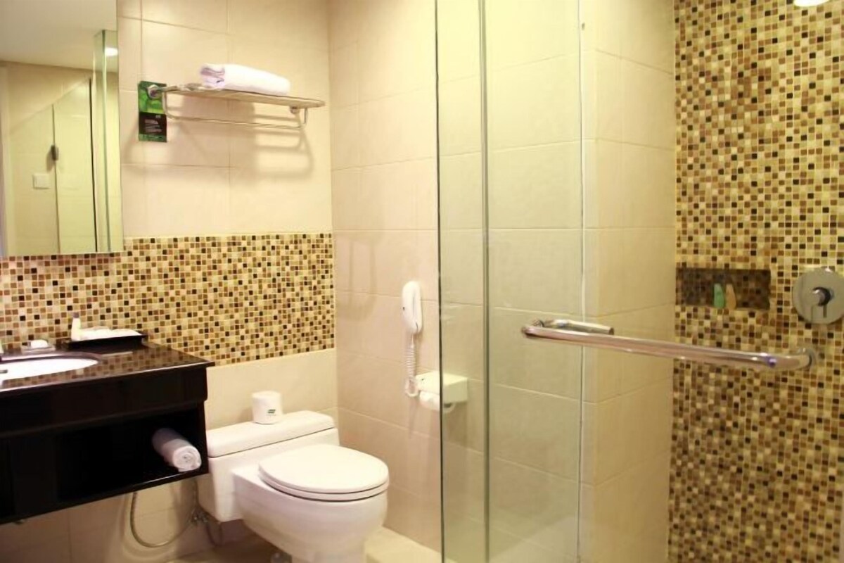 A bathroom with a toilet, sink, and a glass shower enclosure.