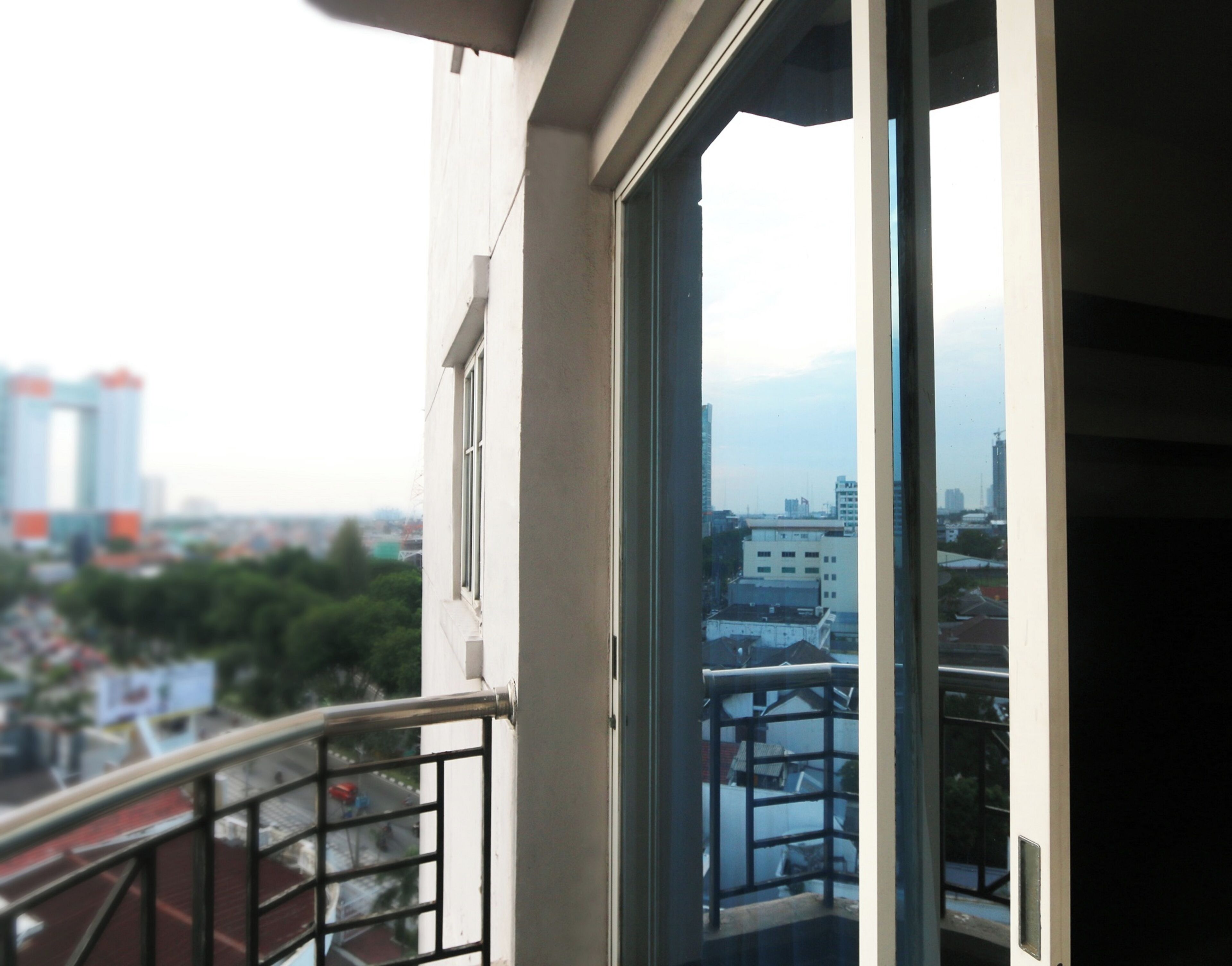 Un balcón con vista a un paisaje urbano, que incluye edificios y un río.