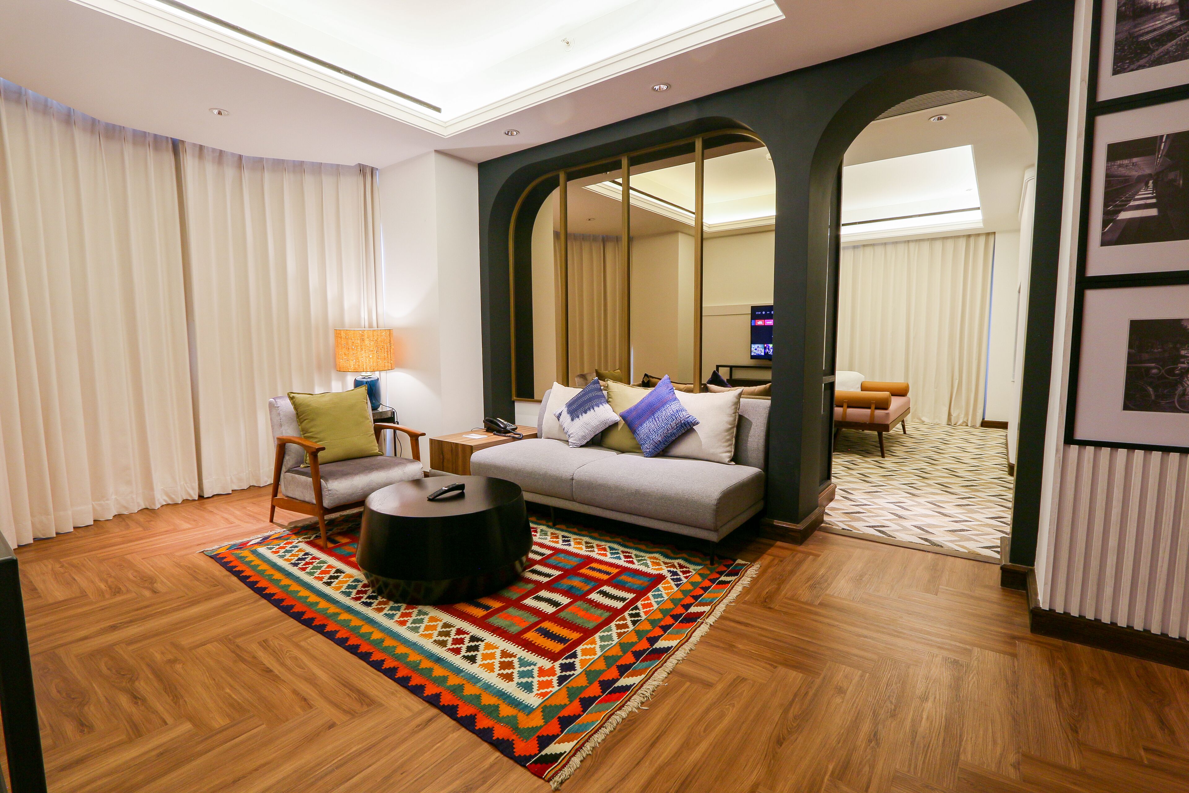 A modern living room with a sofa, armchairs, a coffee table, and a patterned rug.