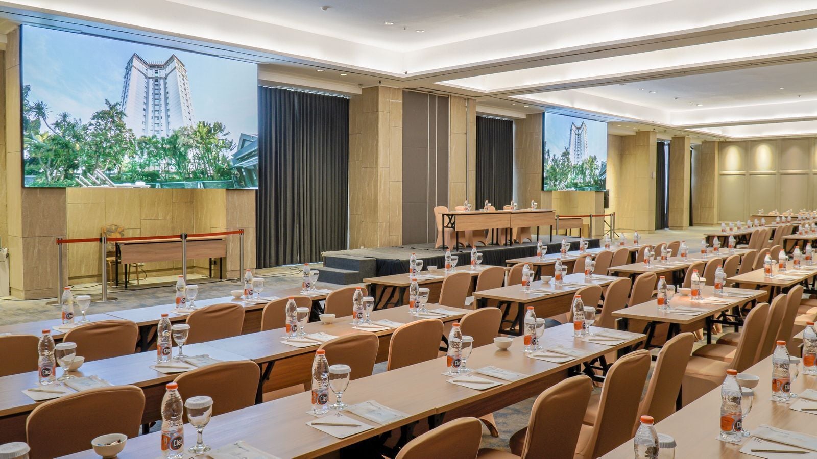 A conference room with multiple tables, chairs, and a stage.