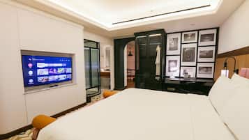 A hotel room with a bed, a desk, a television, and a wall with framed pictures.