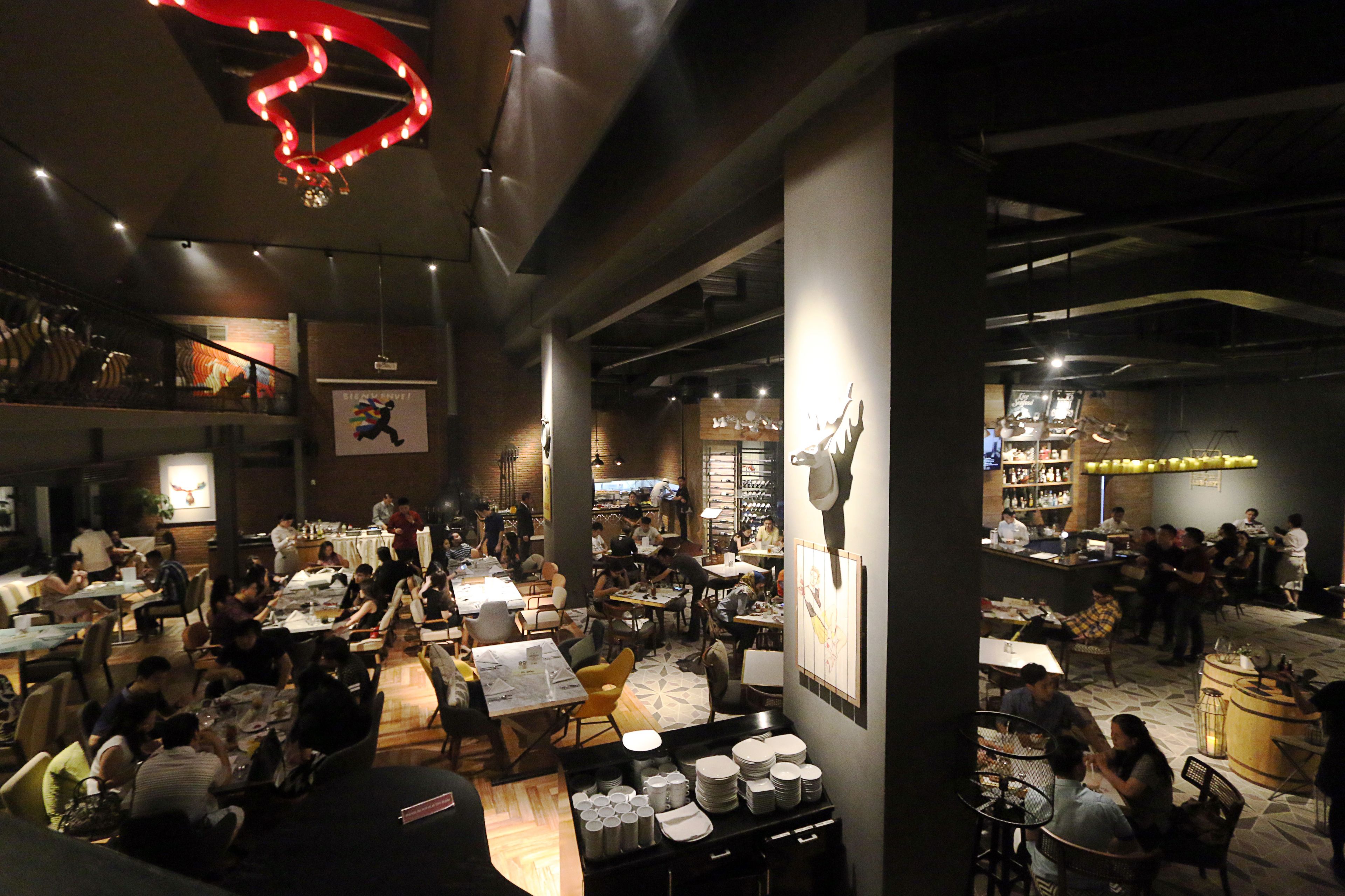 A spacious restaurant with multiple dining areas, high ceilings, and modern lighting fixtures.