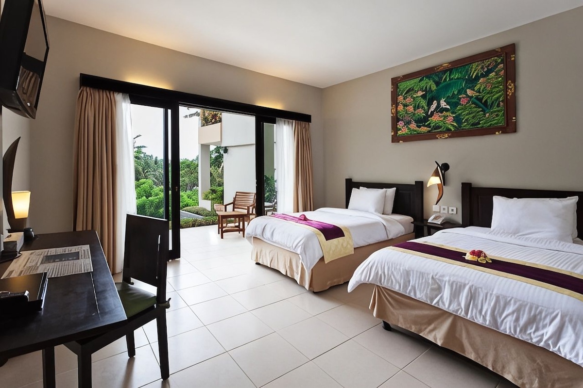 A hotel room with two beds, a desk, and a view of the outdoors.