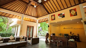 Un'ampia hall con soffitto alto, sedute confortevoli, una reception e opere d'arte alle pareti.