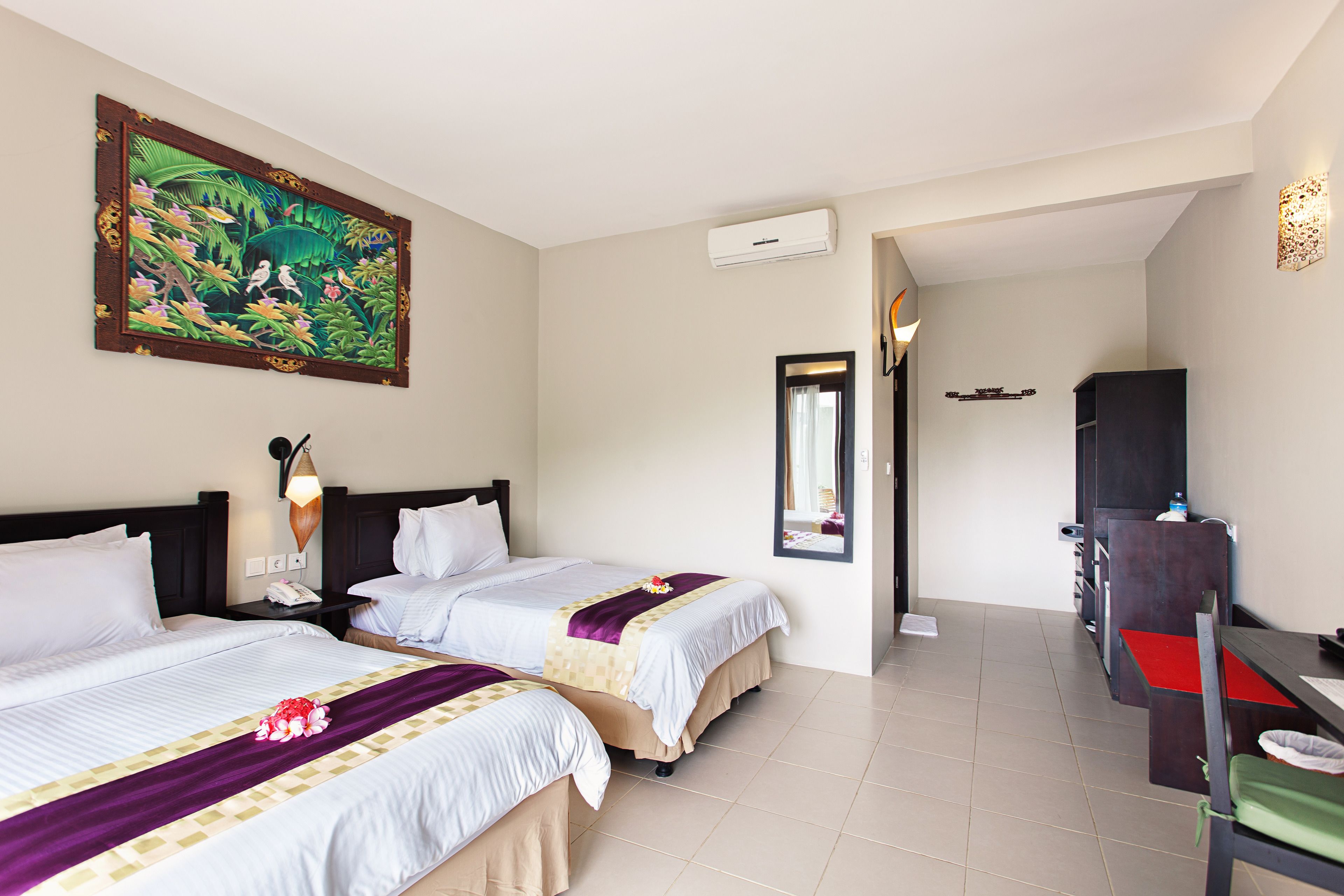 Habitación de hotel con dos camas, un cuadro grande, un equipo de aire acondicionado, un escritorio y una silla.