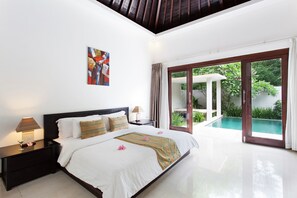 A modern bedroom with a large bed, a nightstand with a lamp, and a view of a swimming pool through a glass door. - Kebun Villas & Resort (Senggigi)
