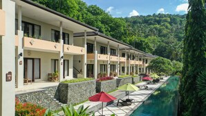 Un hotel con diversi balconi, una piscina e rigogliosa vegetazione sullo sfondo.