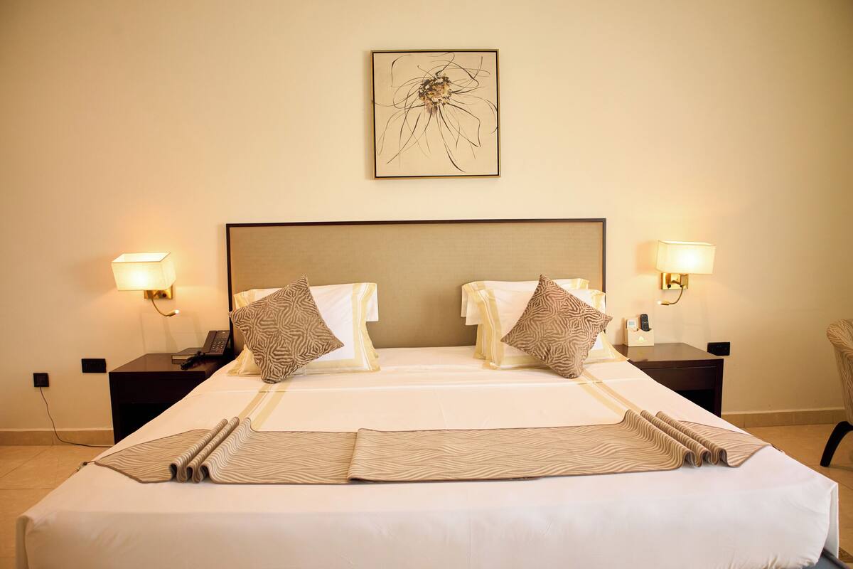 A neatly made bed with patterned pillows, two bedside tables with lamps, and a framed artwork on the wall.