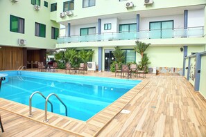 Una piscina al aire libre, sombrillas, tumbonas