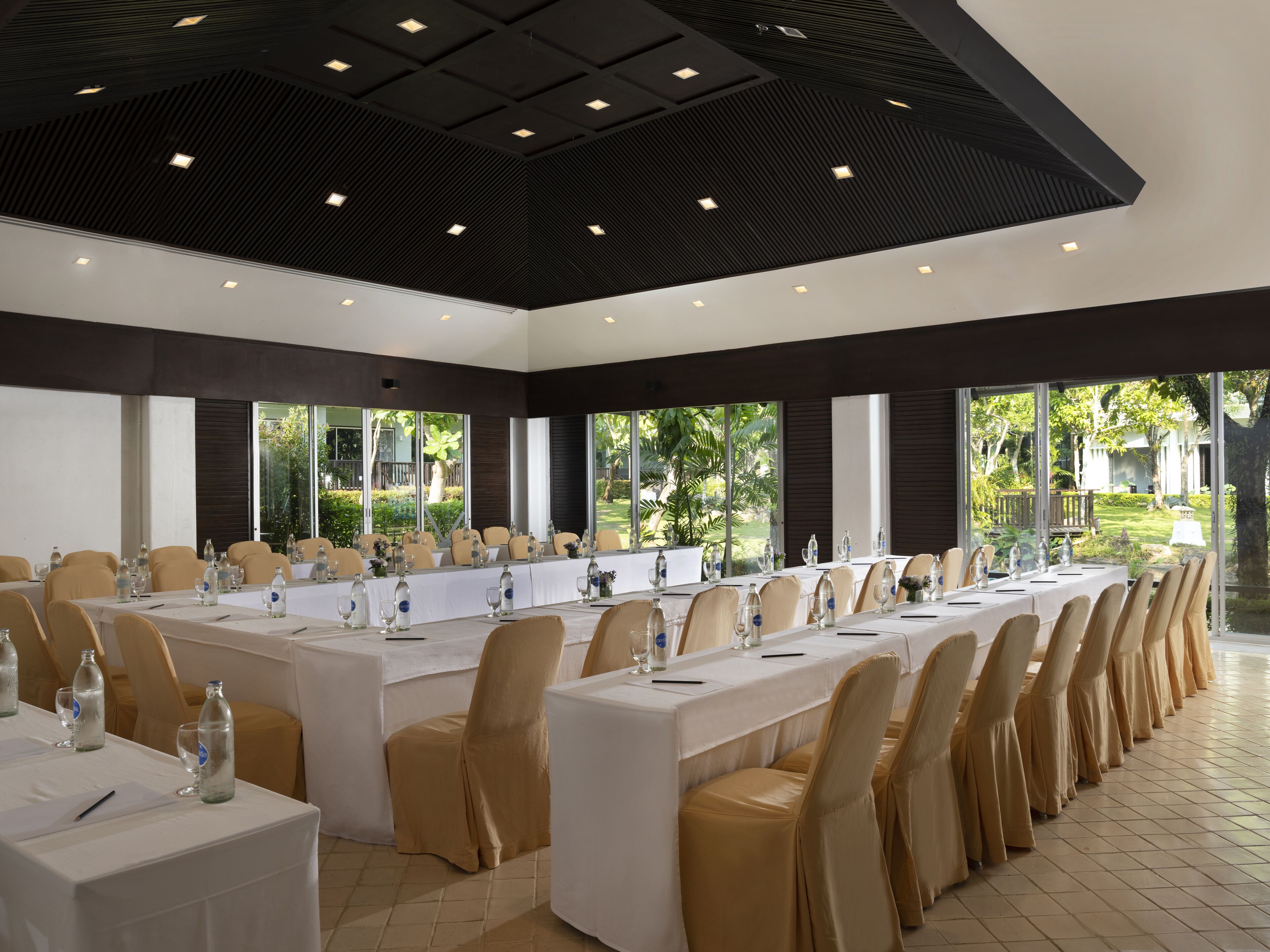 A conference room with long tables, chairs, and a view of the outdoors.