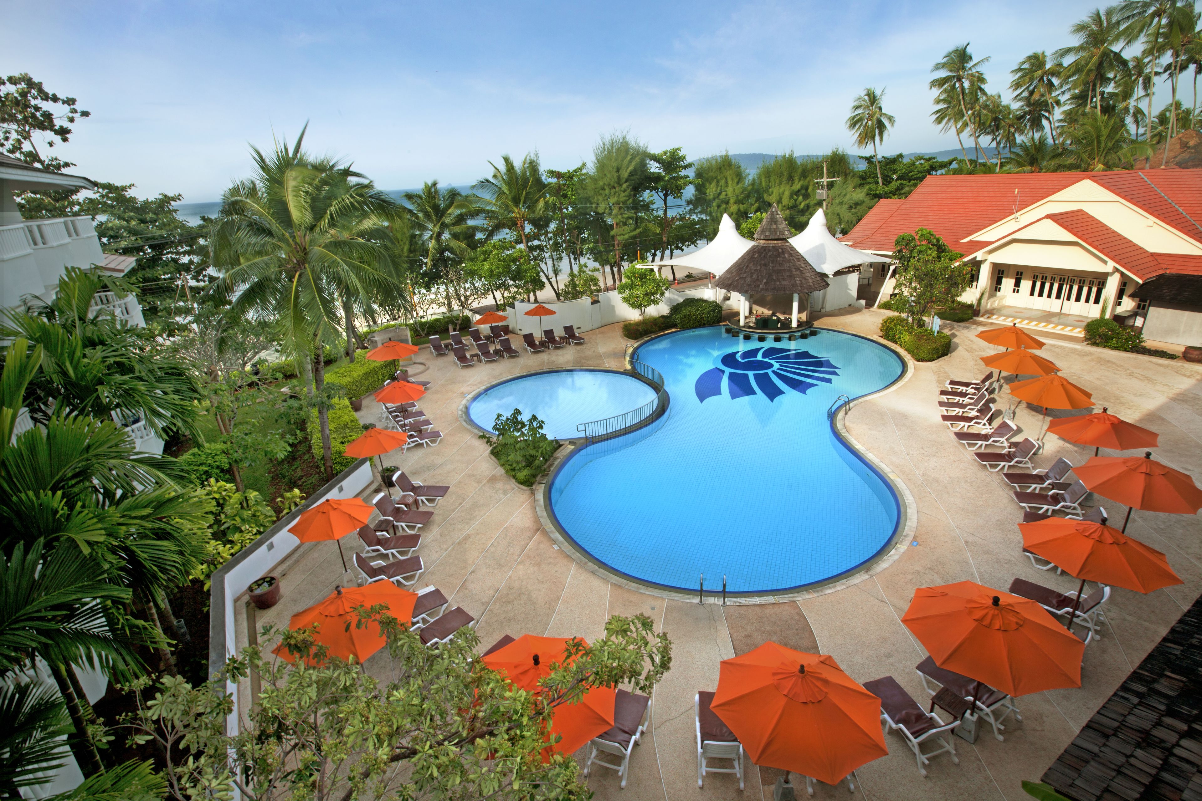 Un resort con una piscina grande, sillas de descanso y sombrillas.
