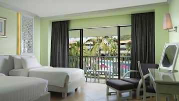 Camera d'albergo con due letti, un balcone vista piscina e una scrivania con lampada.