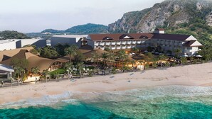 Un hotel sulla spiaggia con diversi edifici, una spiaggia sabbiosa e acque turchesi cristalline.