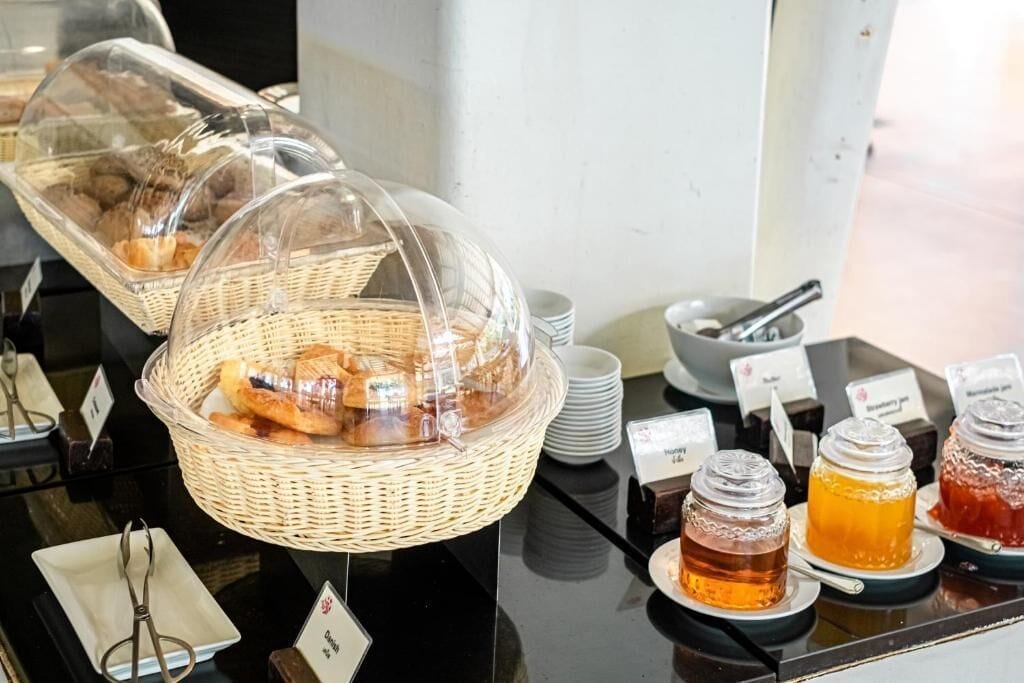 Een buffetopstelling met manden vol gebak, een kom met bestek en gemarkeerde sauzen.