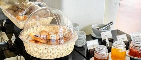 Een buffetopstelling met manden vol gebak, een kom met bestek en gemarkeerde sauzen.