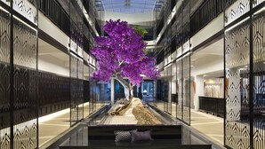Un moderno atrio con una fontana centrale, un albero decorativo e un'area salotto.