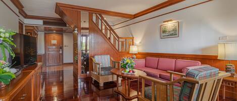 A spacious living room with a wooden staircase, a sofa, and a television.