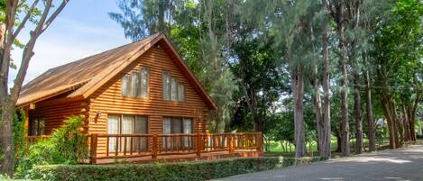 Una cabaña de troncos con terraza de madera y entrada de adoquines.