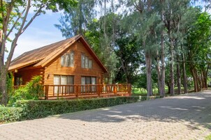 Eine Holzhütte mit einer Holzterrasse und einem gepflasterten Auffahrtsweg.