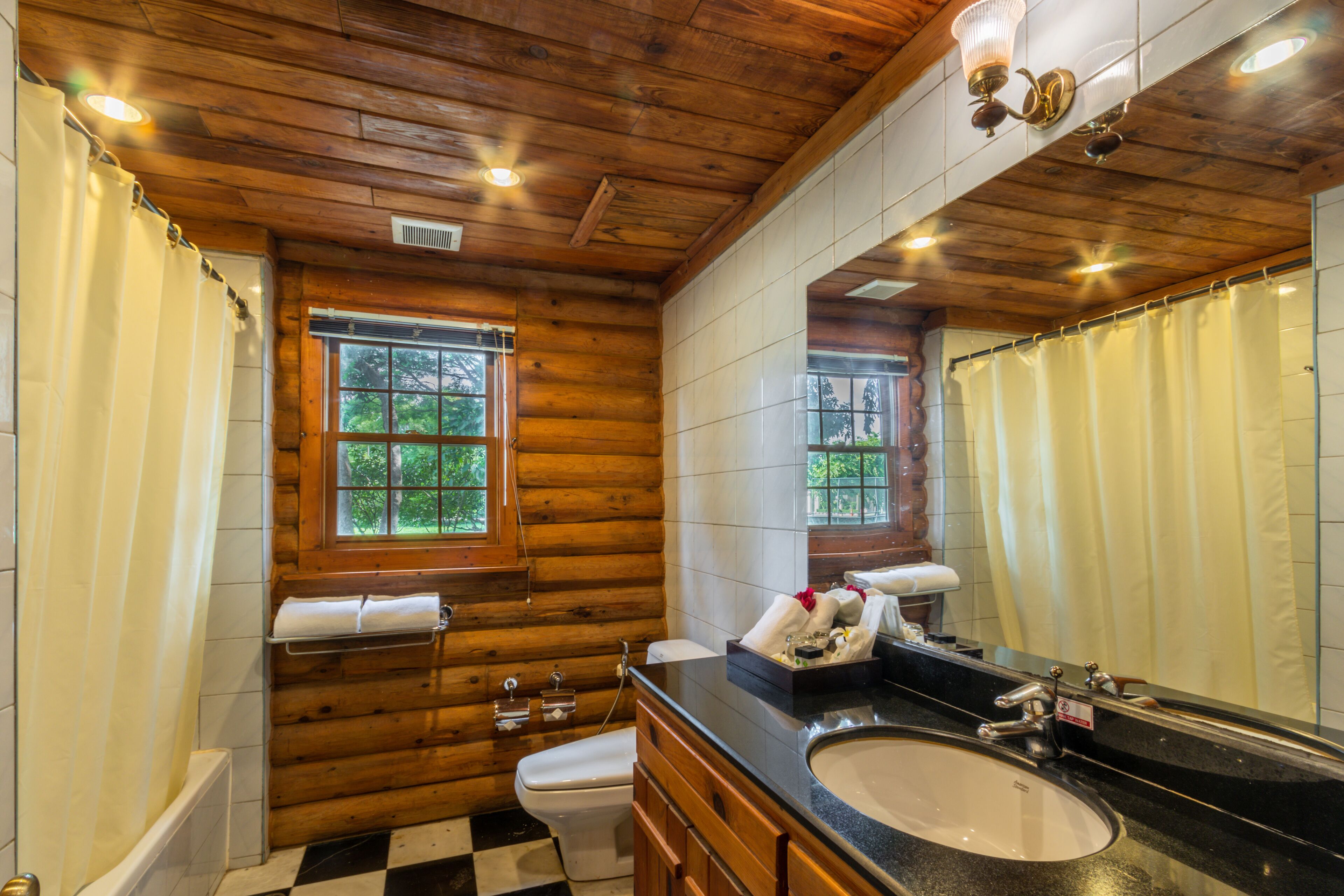 A wooden cabin bathroom with a large mirror, a sink, and a toilet.