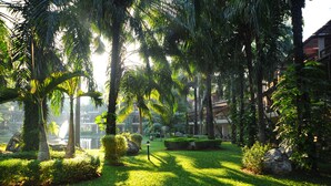 Een weelderige tuin met palmbomen, een fontein en verzorgde hagen.