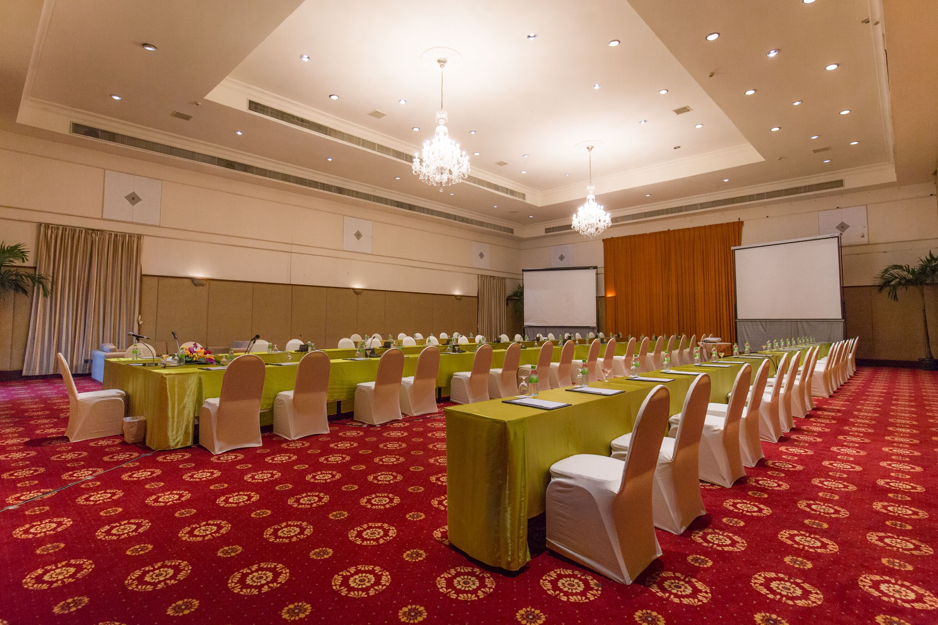 Una sala conferenze con file di tavoli, sedie e uno schermo per proiezioni.