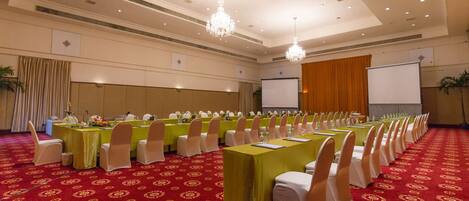 A conference room with rows of tables, chairs, and a projector screen.