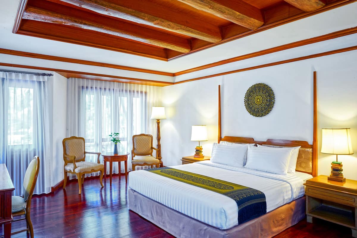 Ein Hotelzimmer mit einem großen Bett, zwei Sesseln, einem kleinen Tisch und einer dekorativen Wandgestalt.