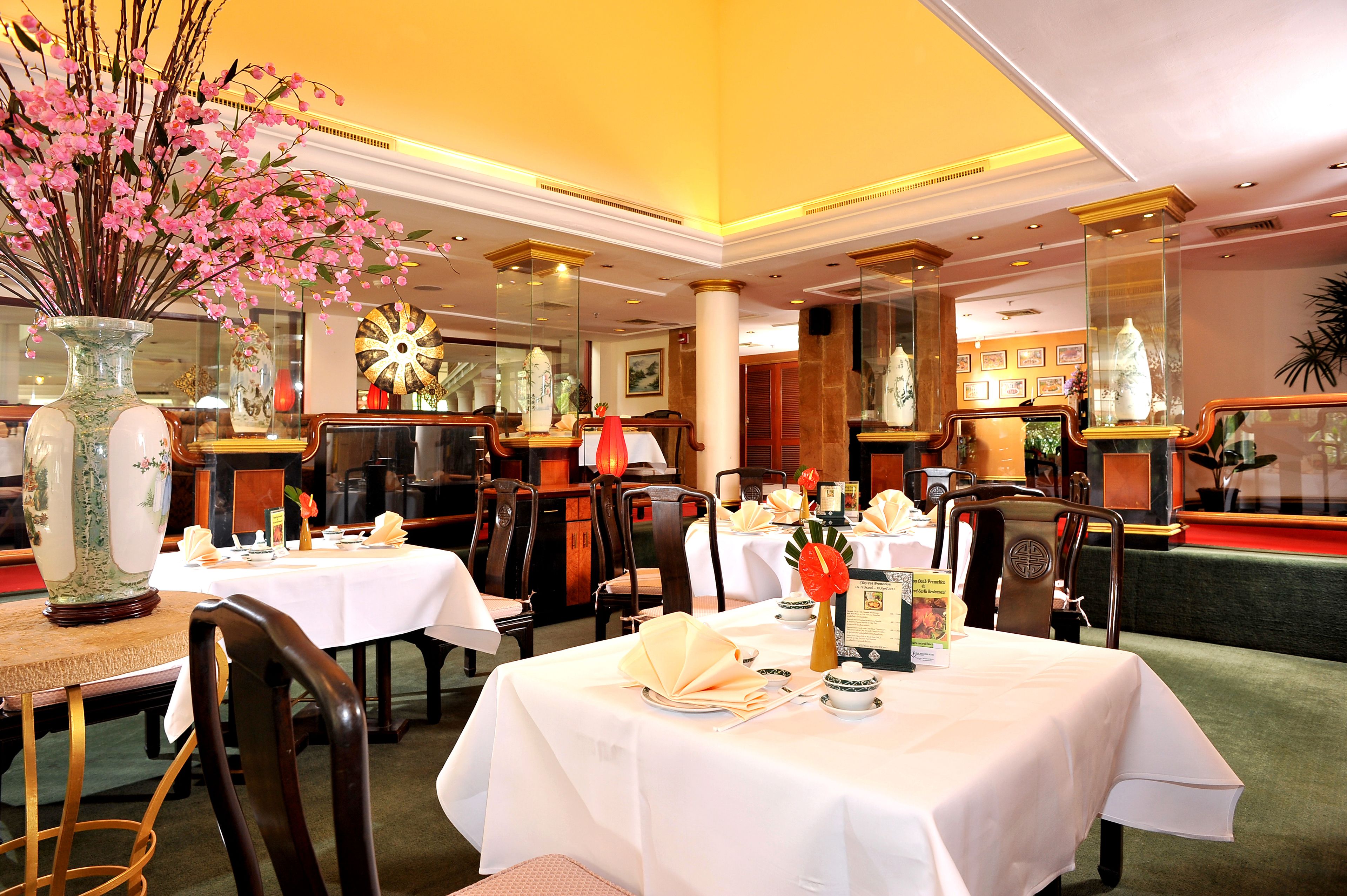 Un restaurante con varias mesas dispuestas para comer, con manteles blancos y platos ordenados.