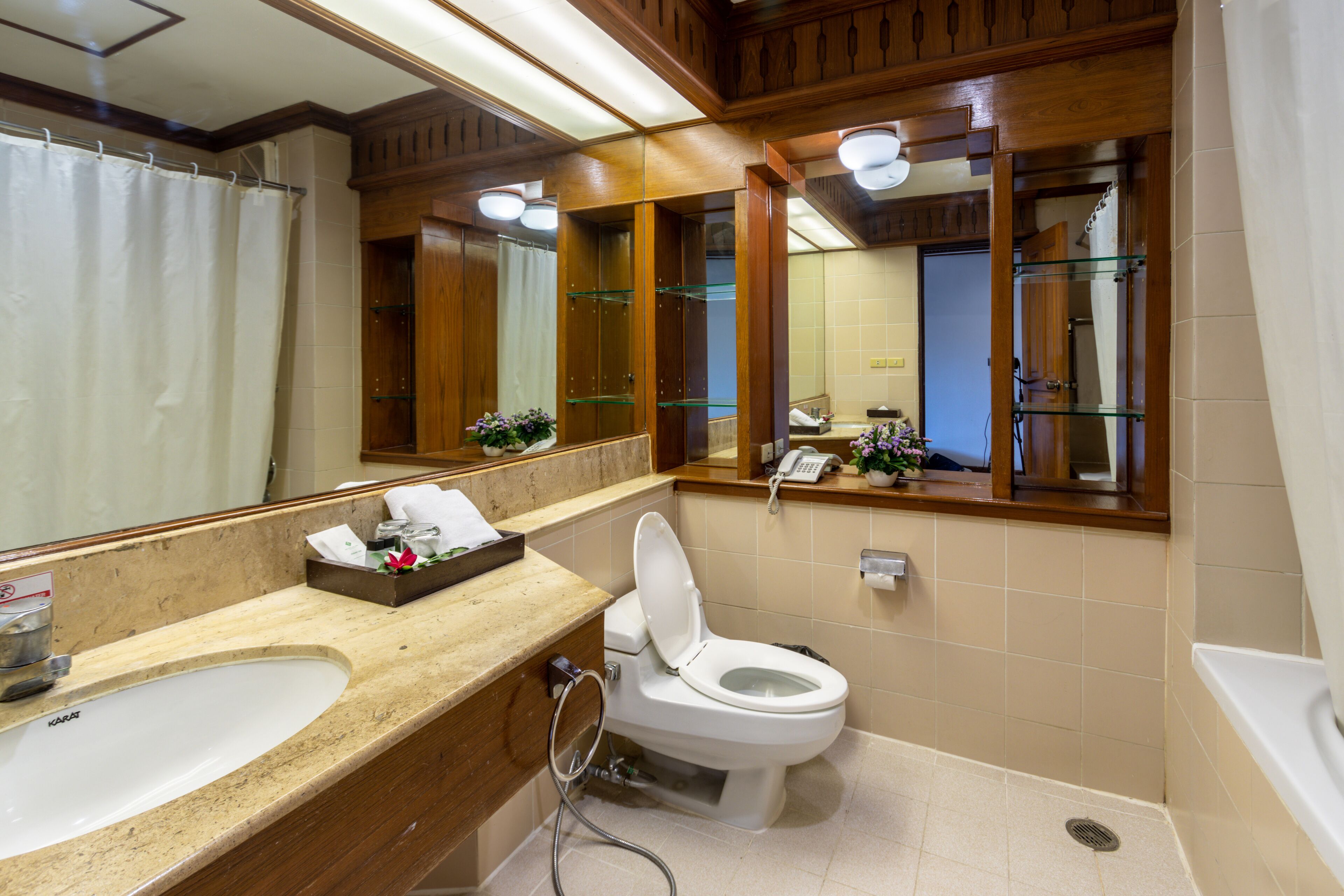 A bathroom with a white sink, a toilet, and a large mirror.